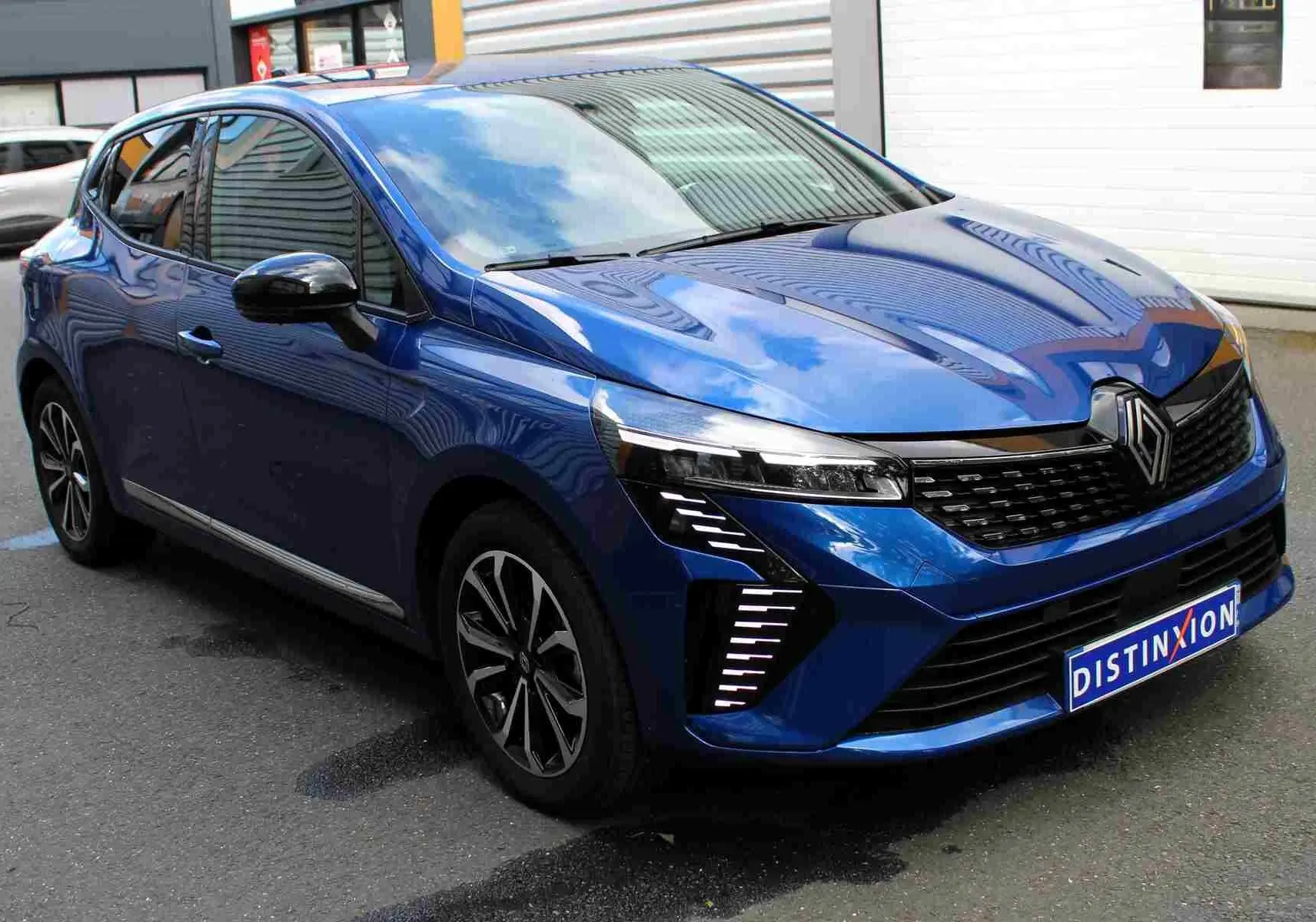 Vue arrière d'une Renault Clio bleu iron metal 2025 avec logo distinctif et plaque d'immatriculation Distinxion.