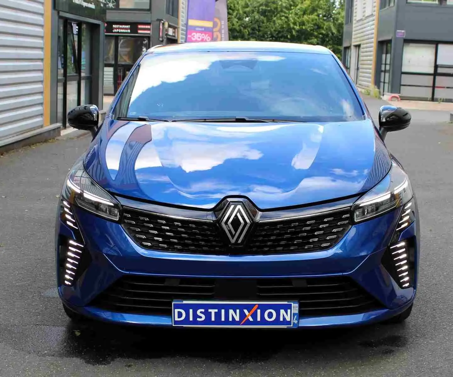 Renault Clio V E-Tech hybride bleu Iron Metal vue 3/4 avant avec feux LED et jantes alliage distinctives.