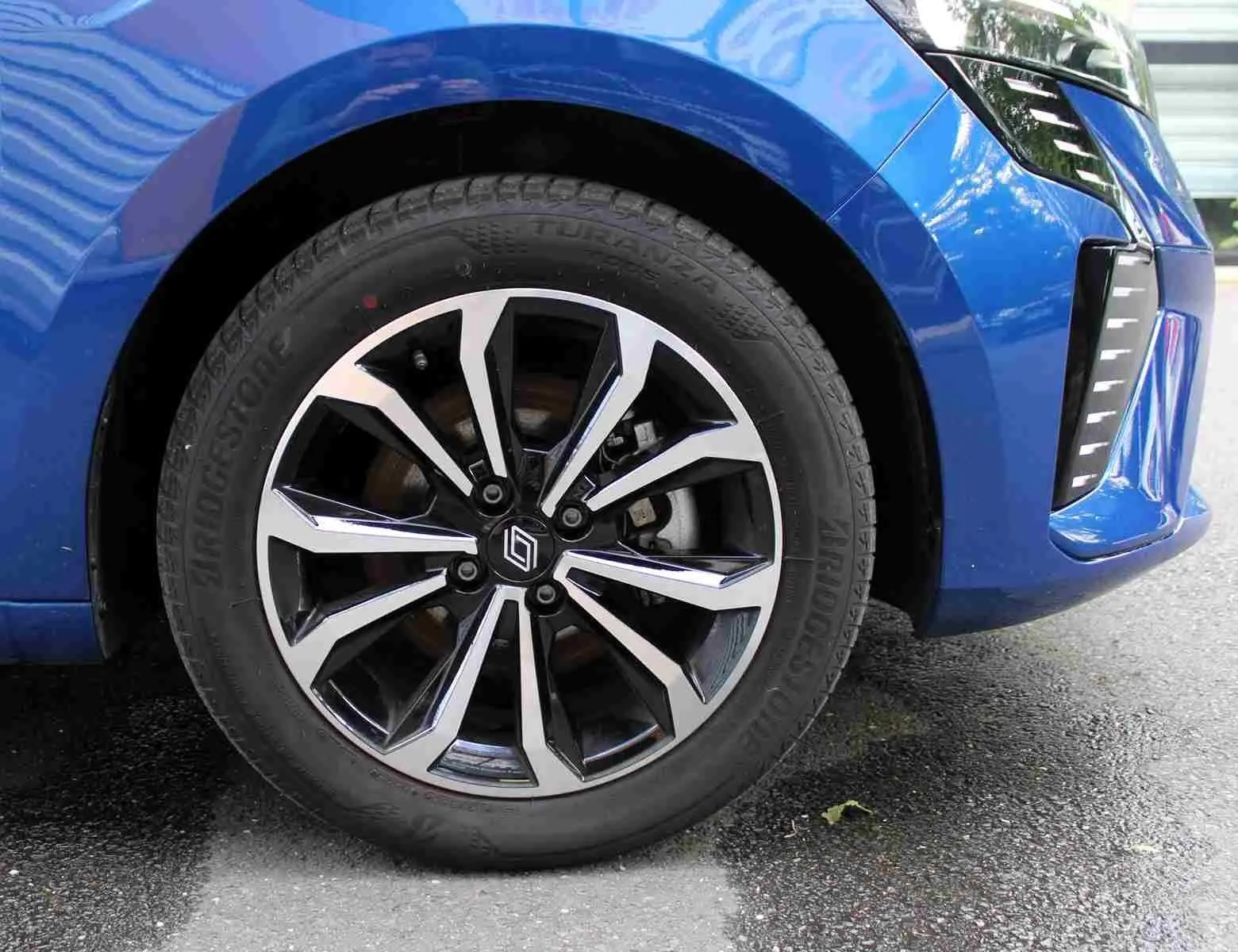 Vue frontale d'une Renault Clio 2025 bleu iron metal avec calandre noire et feux LED verticaux allumés.