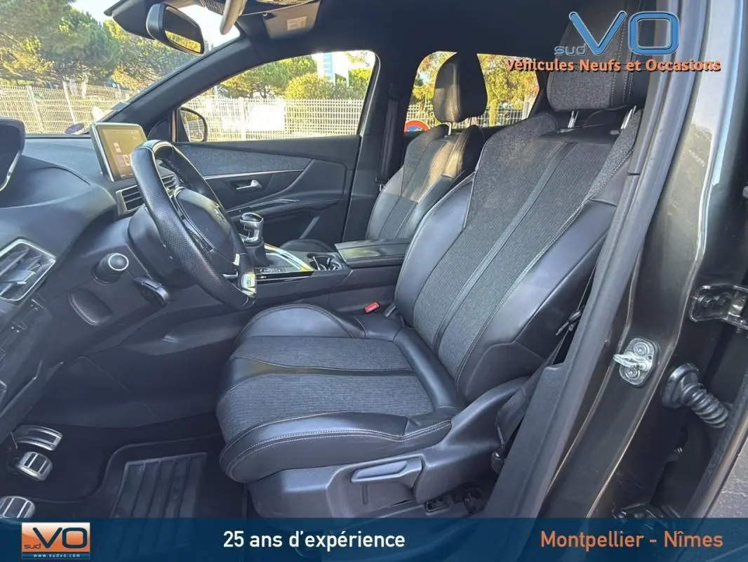 Intérieur avant droit du Peugeot 3008 gris foncé 2018, sièges cuir et tissu, volant cuir et console centrale visible.