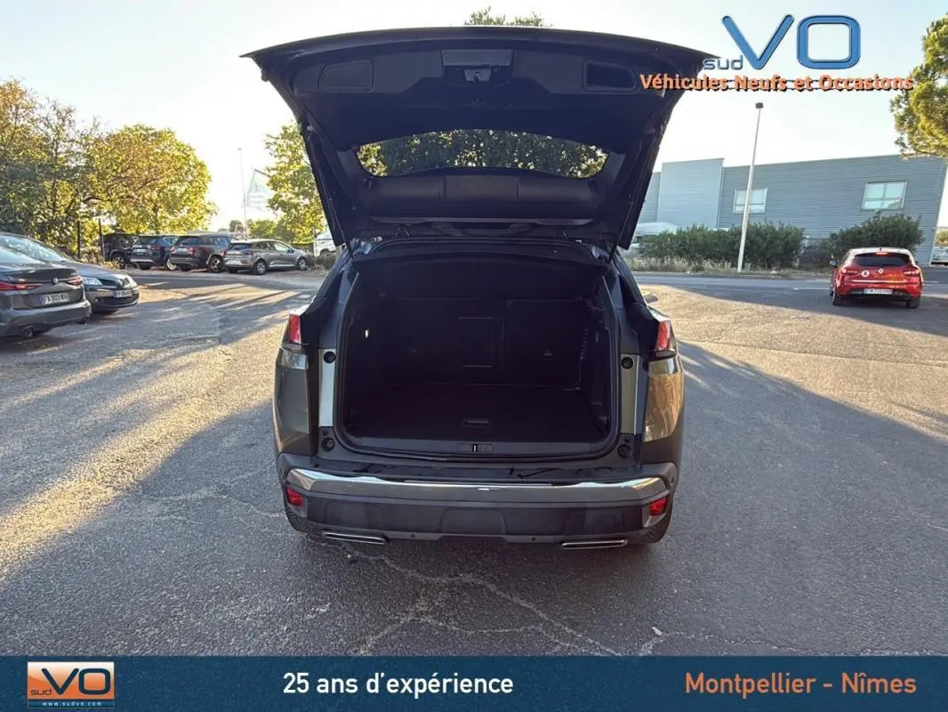 Vue arrière d’un Peugeot 3008 gris foncé 2018 avec coffre ouvert, stationné en extérieur sur parking.
