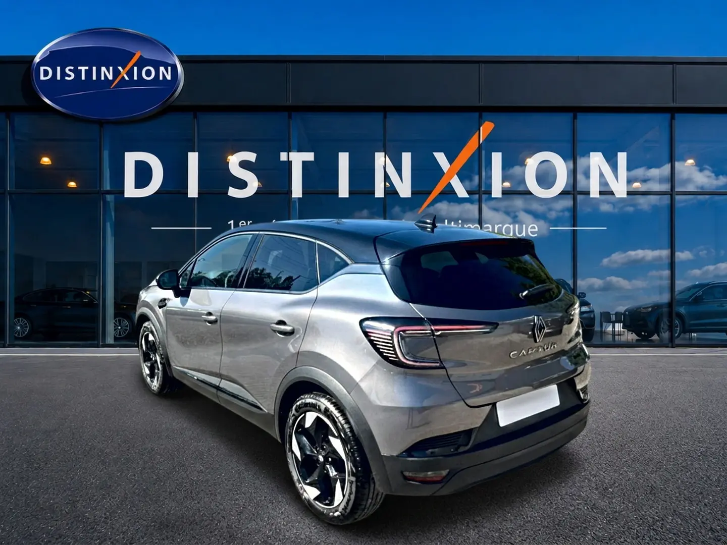 Renault Captur gris cassiopée en 3/4 arrière droit, avec jantes alu et toit noir devant vitrine Distinxion.
