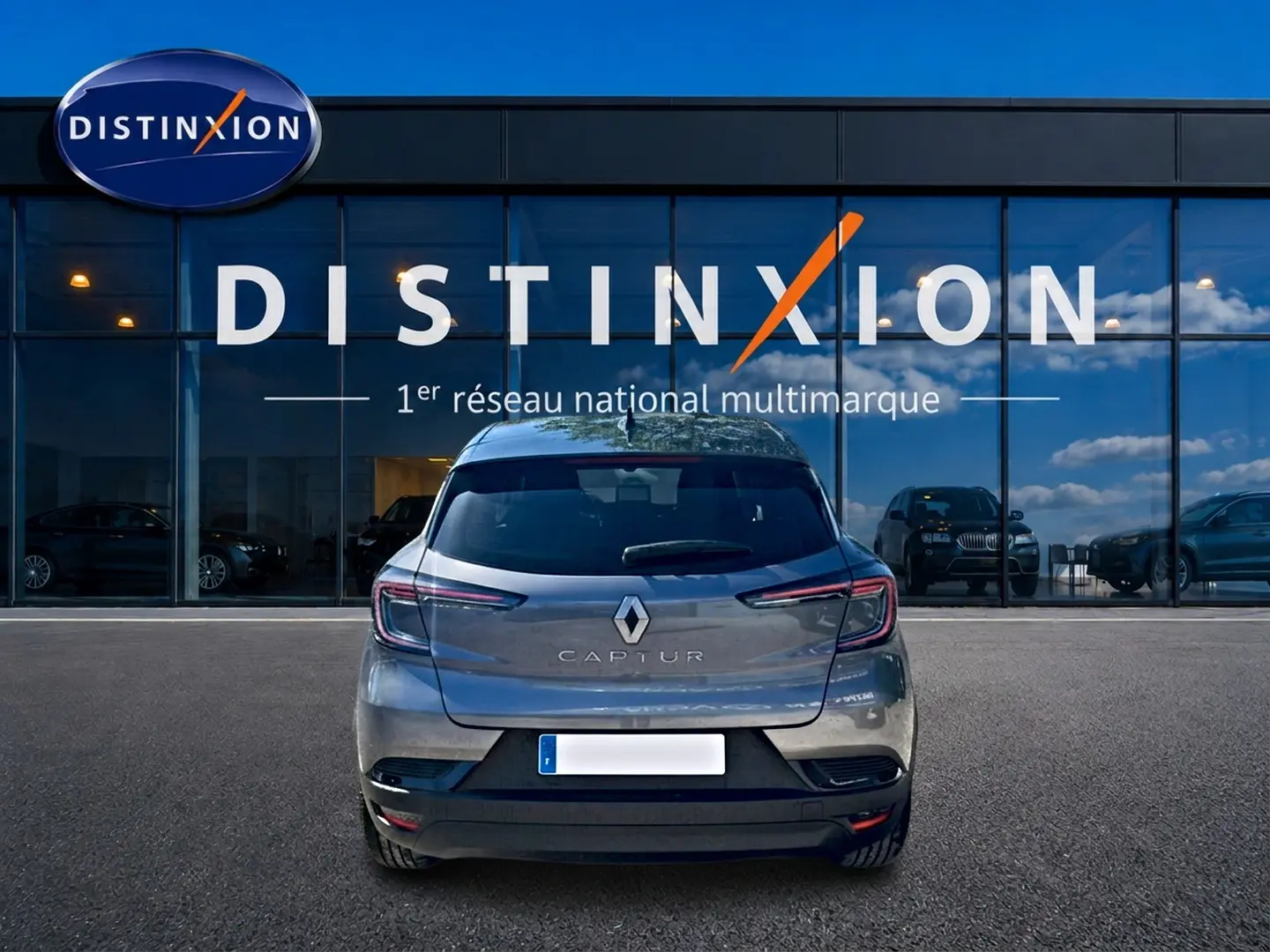 Vue arrière d'un Renault Captur gris cassiopée 2026, avec feux LED et logo distinctif sur fond de vitrine Distinxion.