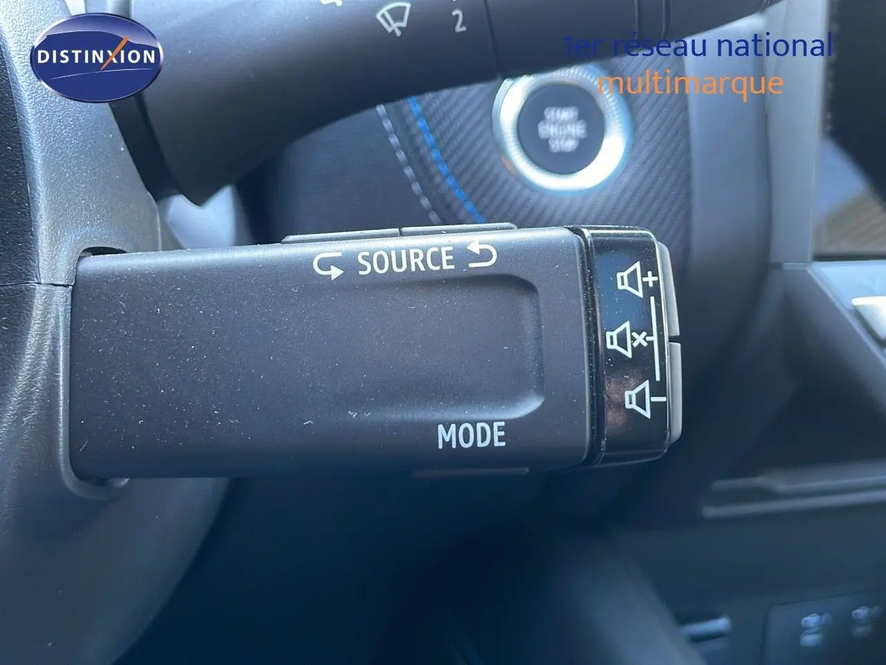 Gros plan sur la commande au volant du Renault Captur E-Tech hybride 2025, avec bouton source et mode visible.