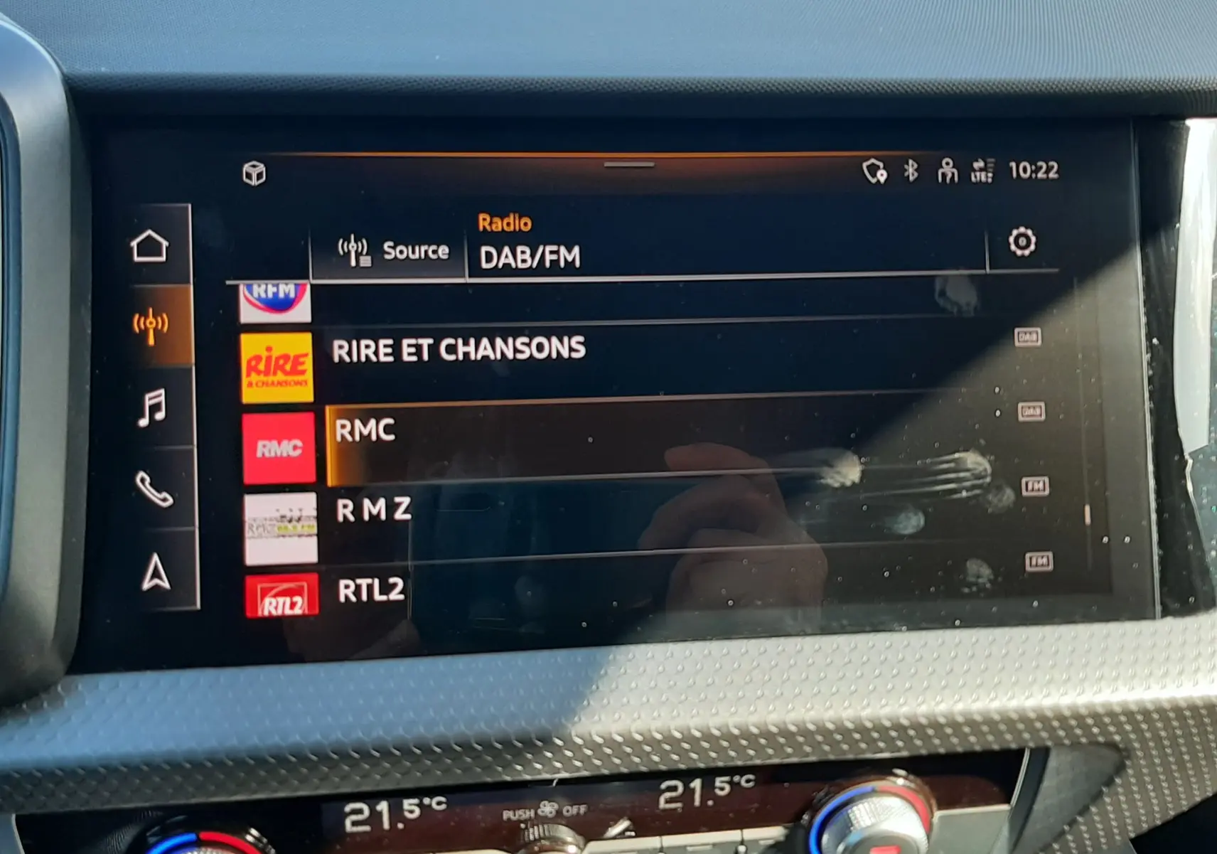 Écran tactile central de l’Audi A1 Sportback 2025 affichant les stations radio DAB/FM, avec commandes de climatisation en dessous.