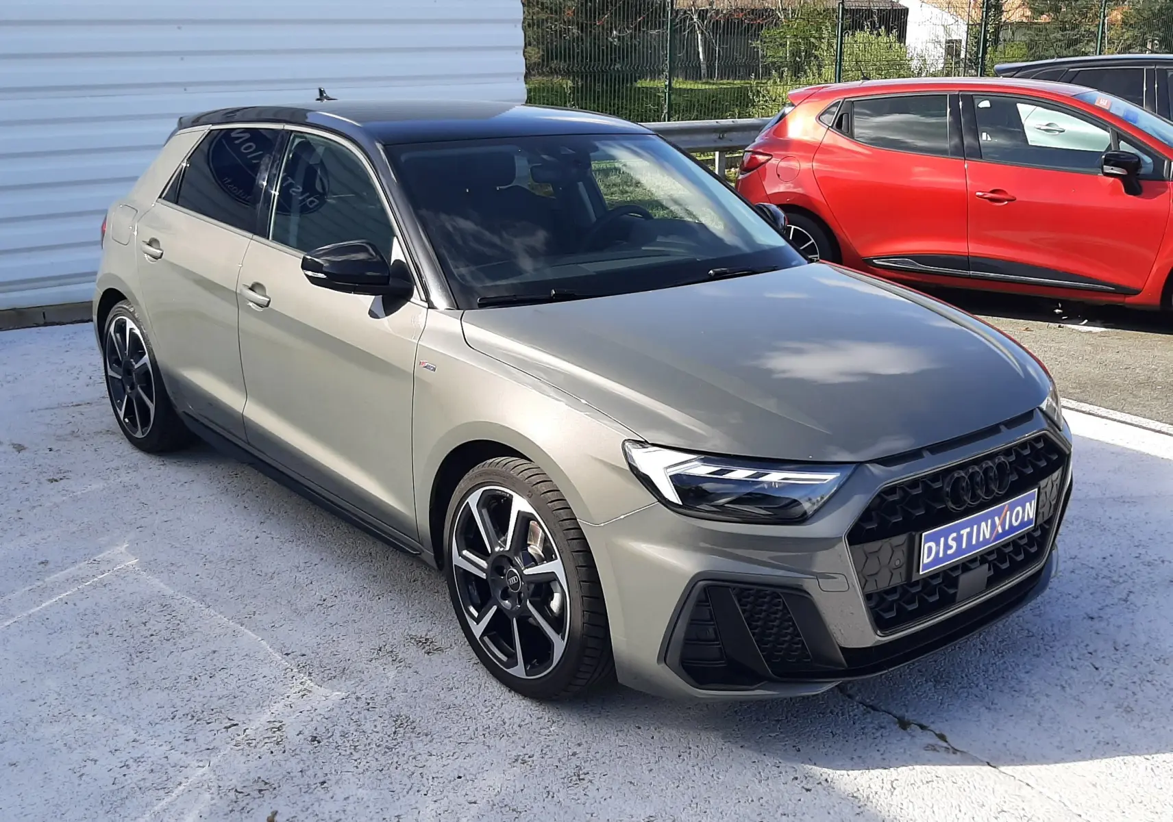 Audi A1 Sportback gris Chronos avec toit noir, vue 3/4 avant droit, jantes alu 18 pouces et calandre noire distinctive.