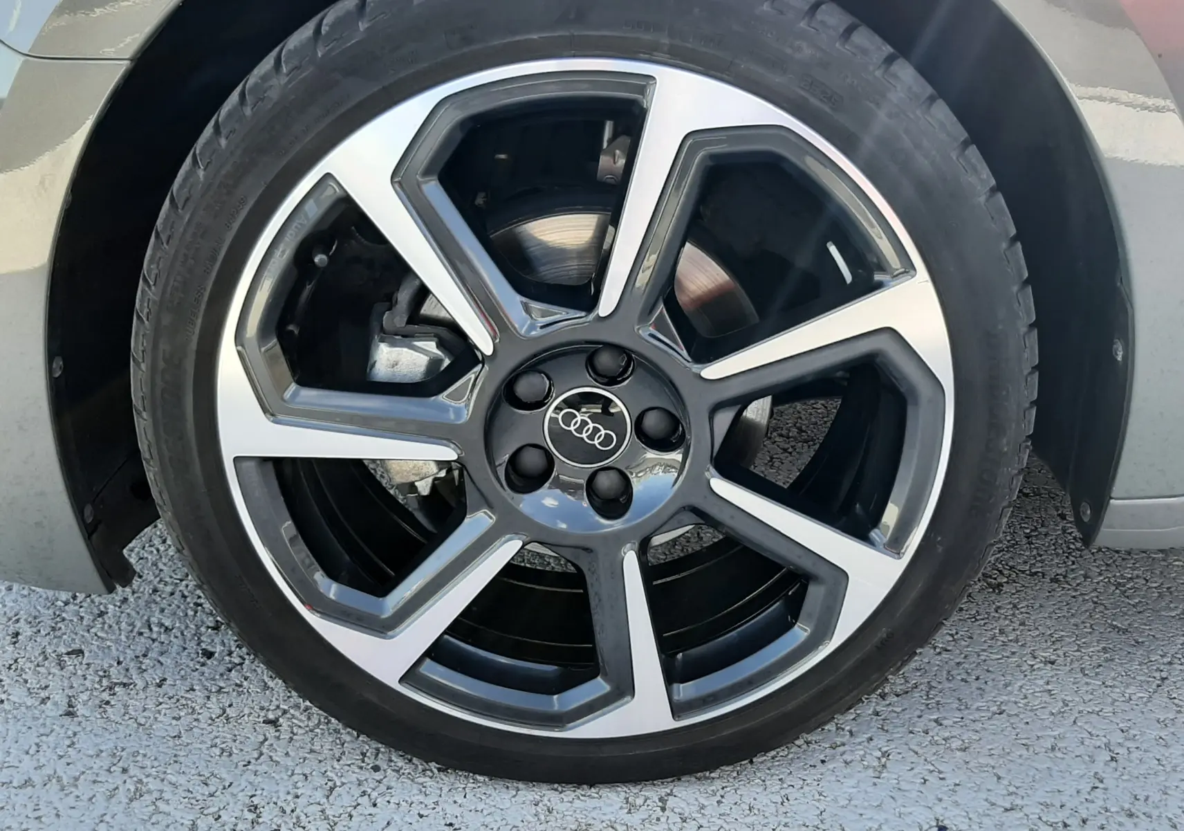 Gros plan sur la jante alu 18 pouces bicolore en hélice d'une Audi A1 Sportback gris Chronos, roue avant droite.