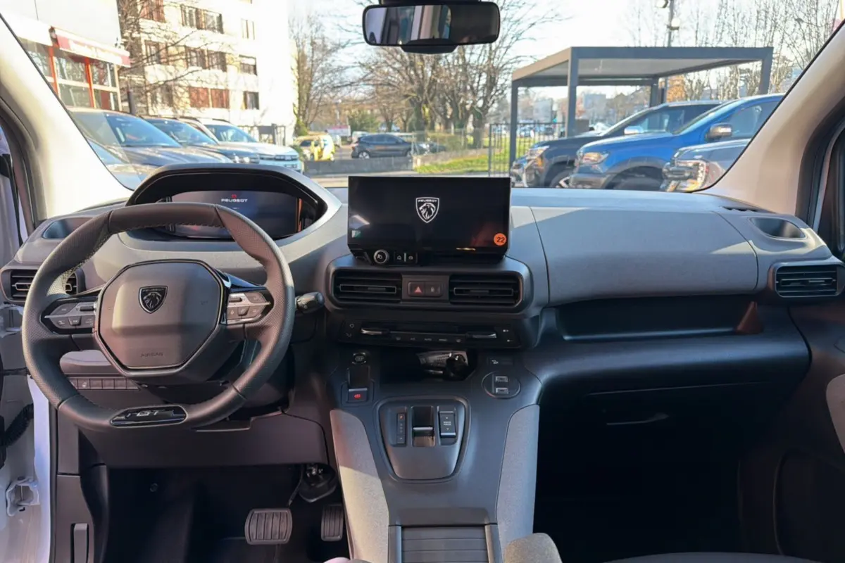 Vue avant de l’intérieur du Peugeot Rifter blanc kaolin 2025, avec volant cuir multifonctions et écran tactile central.