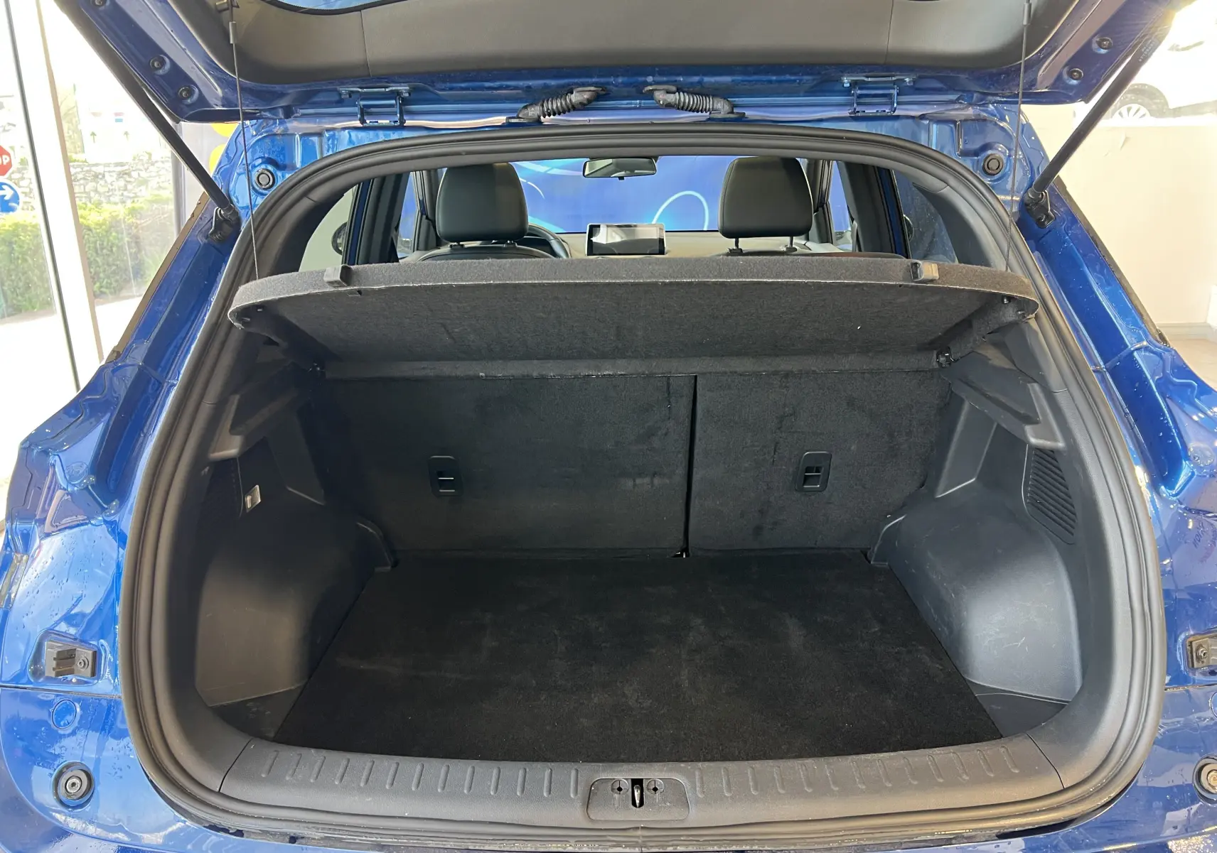 Coffre ouvert vu de l'arrière d'un SERES 3 Electric bleu astral métallisé, montrant l'espace de chargement vide.