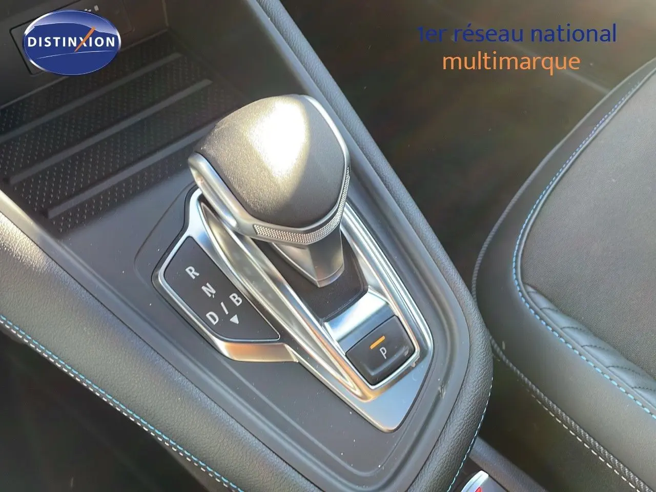 Le levier de vitesses automatique de la Renault Captur E-Tech hybride 2025, avec coutures bleues sur console noire.