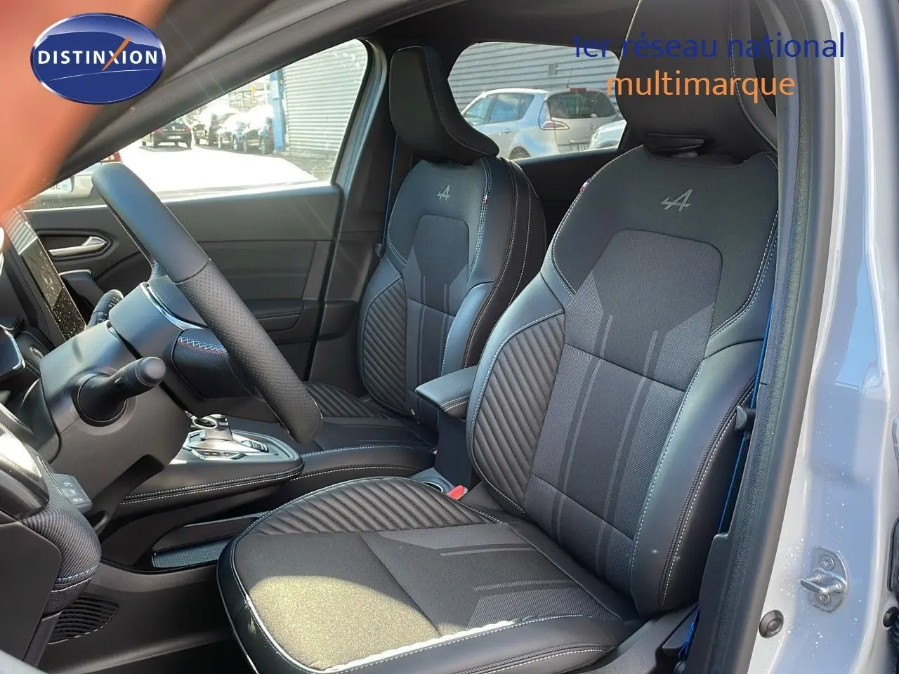 Intérieur avant du Renault Captur E-Tech gris rafale, sièges noirs Alpine avec surpiqûres et volant visible côté gauche.