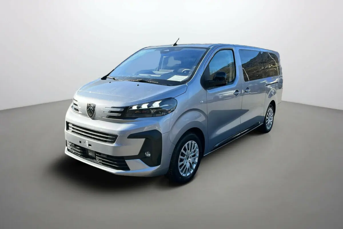 Peugeot Traveller gris acier en 3/4 avant droit, avec vitres surteintées et jantes alliage visibles.