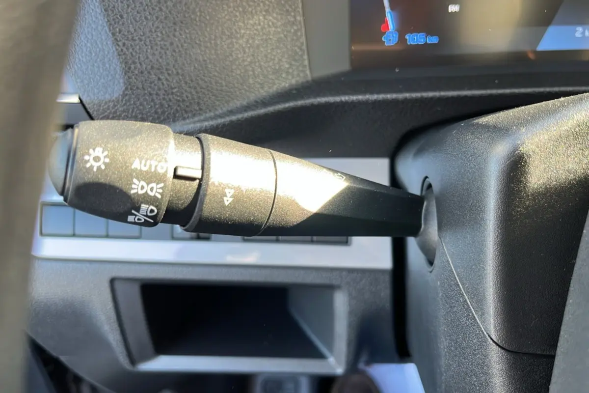 Gros plan sur la commande des feux automatique à gauche du volant dans l’habitacle du Peugeot Traveller gris acier 2025.