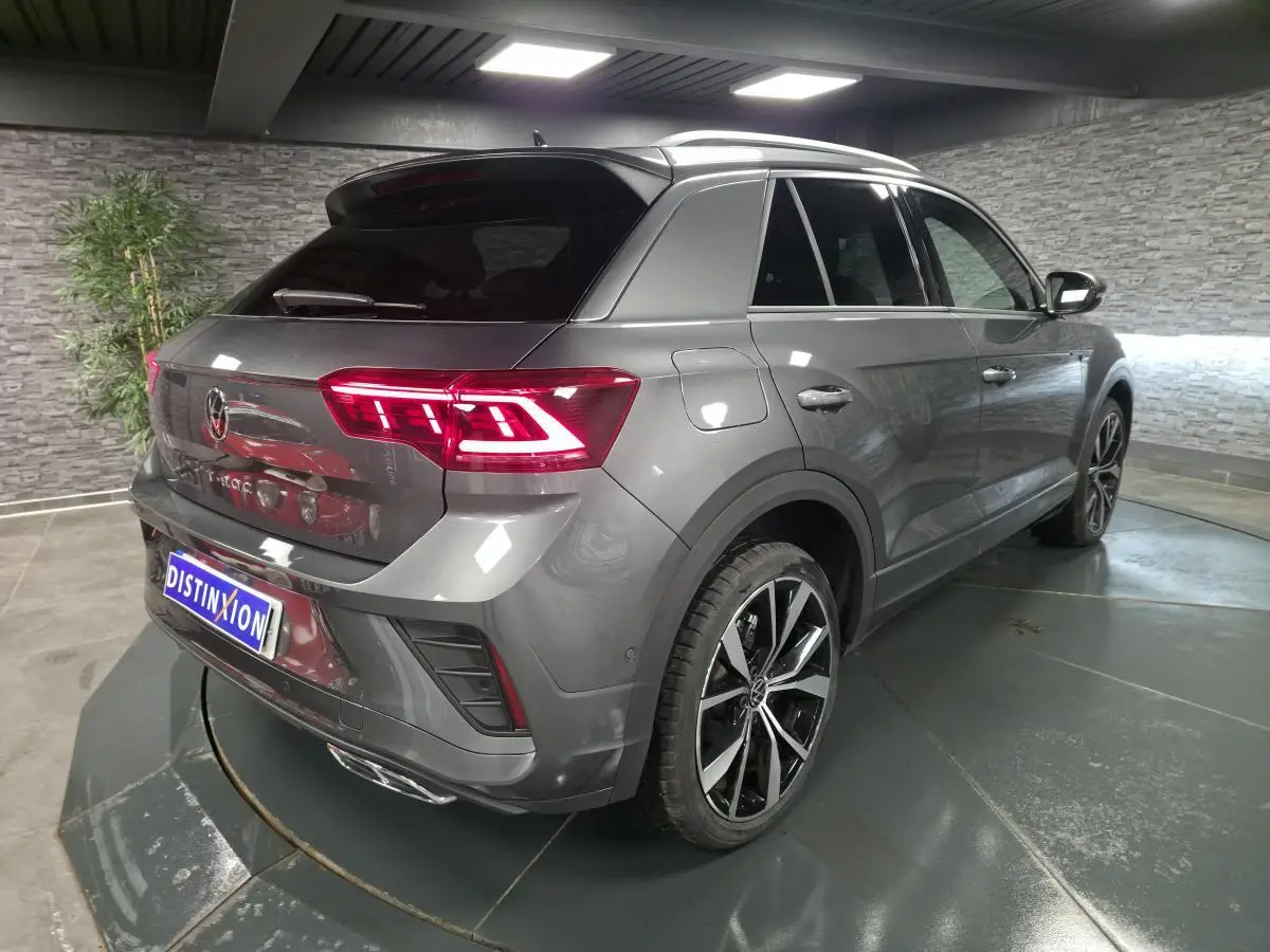 Volkswagen T-Roc 1.5 TSI Evo gris, vue 3/4 arrière droit, avec jantes alliage 19 pouces et feux LED allumés.