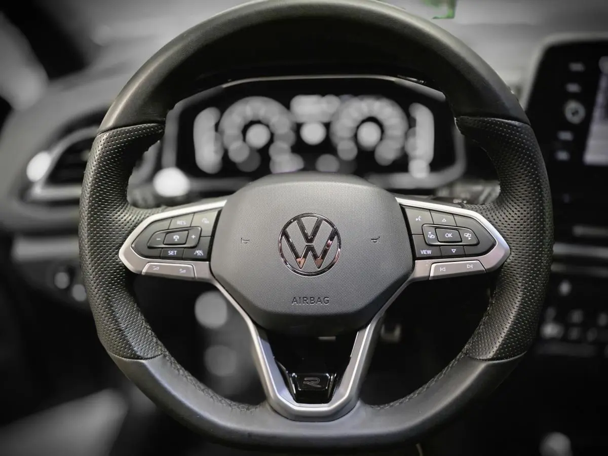 Volant sport en cuir noir avec logo VW et commandes multifonctions du Volkswagen T-Roc 2025, vue frontale rapprochée.