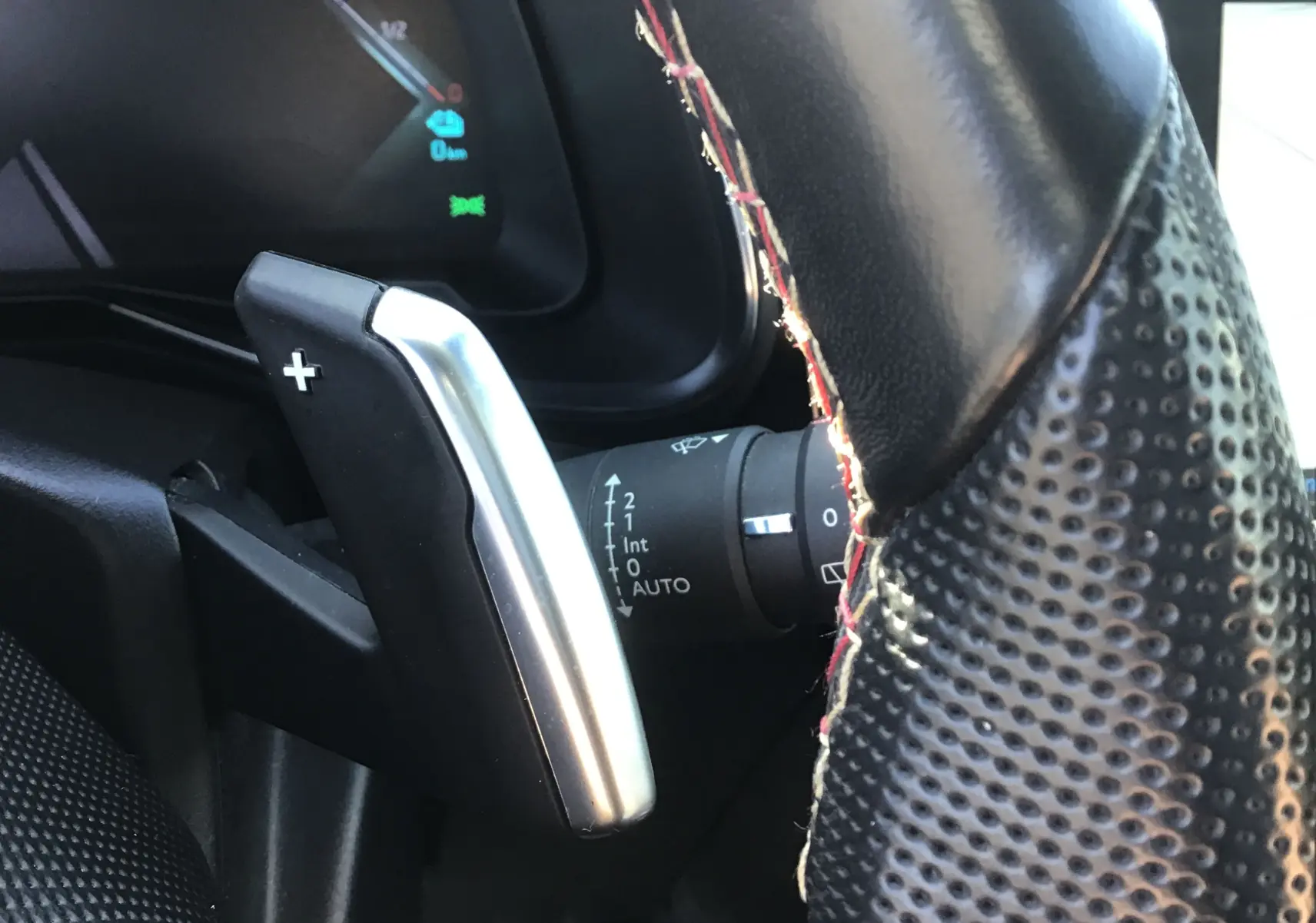 Gros plan sur la palette de changement de vitesse droite en aluminium et cuir perforé du volant noir du DS7 Crossback 2023.