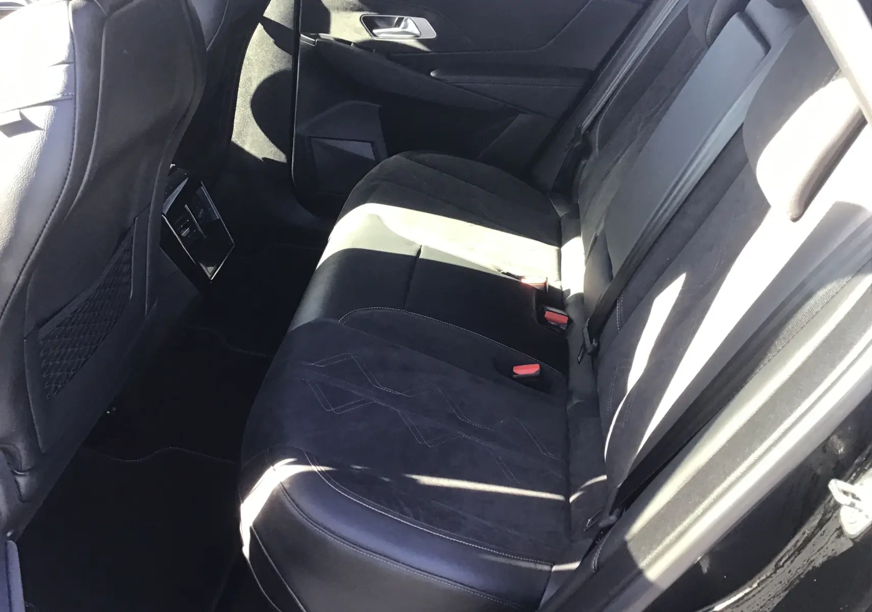 Vue intérieure côté droit des sièges arrière en cuir noir et alcantara du DS7 Crossback 2023, avec ceinture et porte ouvert.