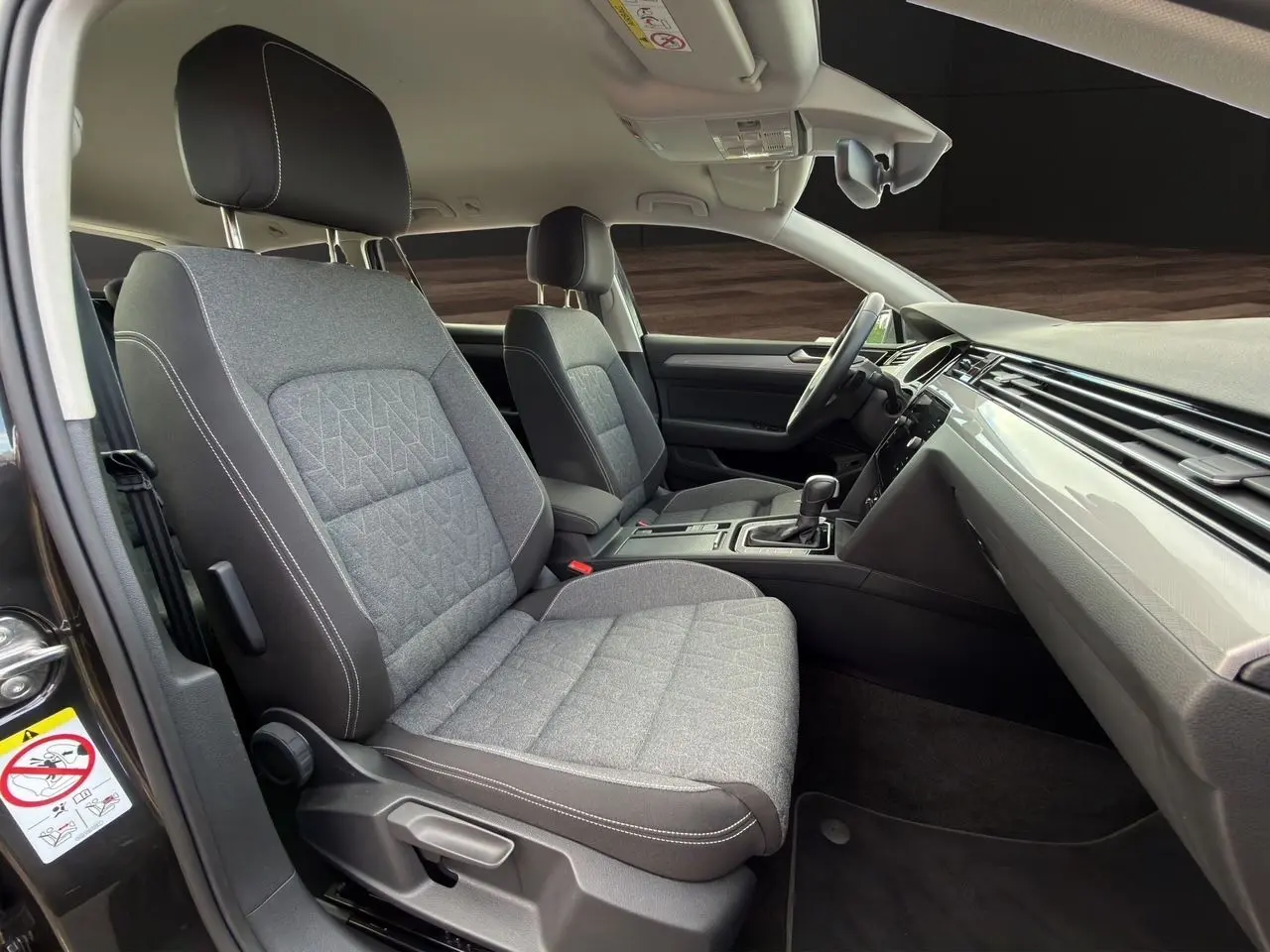 Vue intérieure côté conducteur de la Volkswagen Passat SW 2.0 TDI 2022 avec sièges tissu gris et tableau de bord épuré.