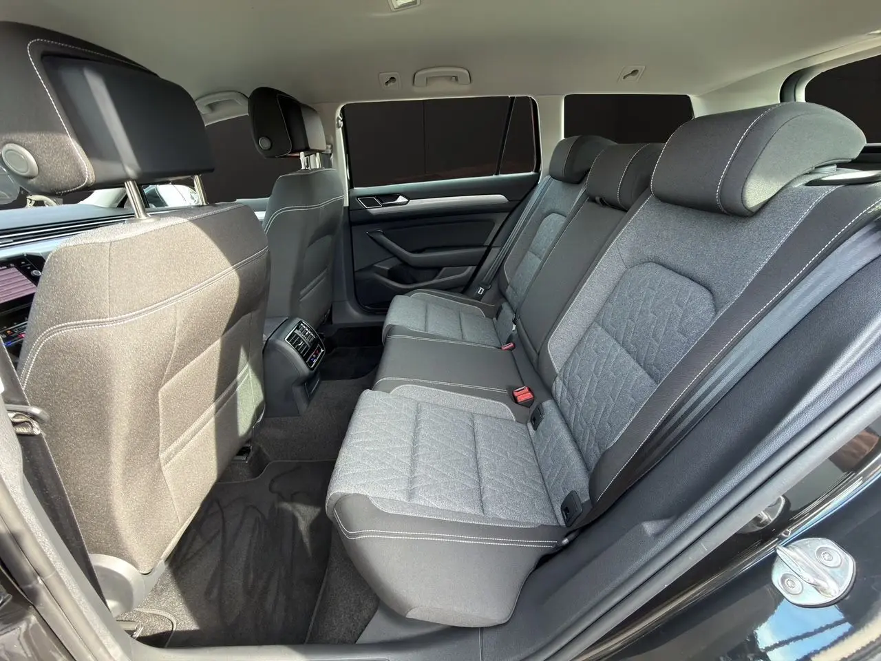 Vue intérieure arrière côté droit de la Volkswagen Passat SW 2.0 TDI avec sièges tissu gris et détails noirs.