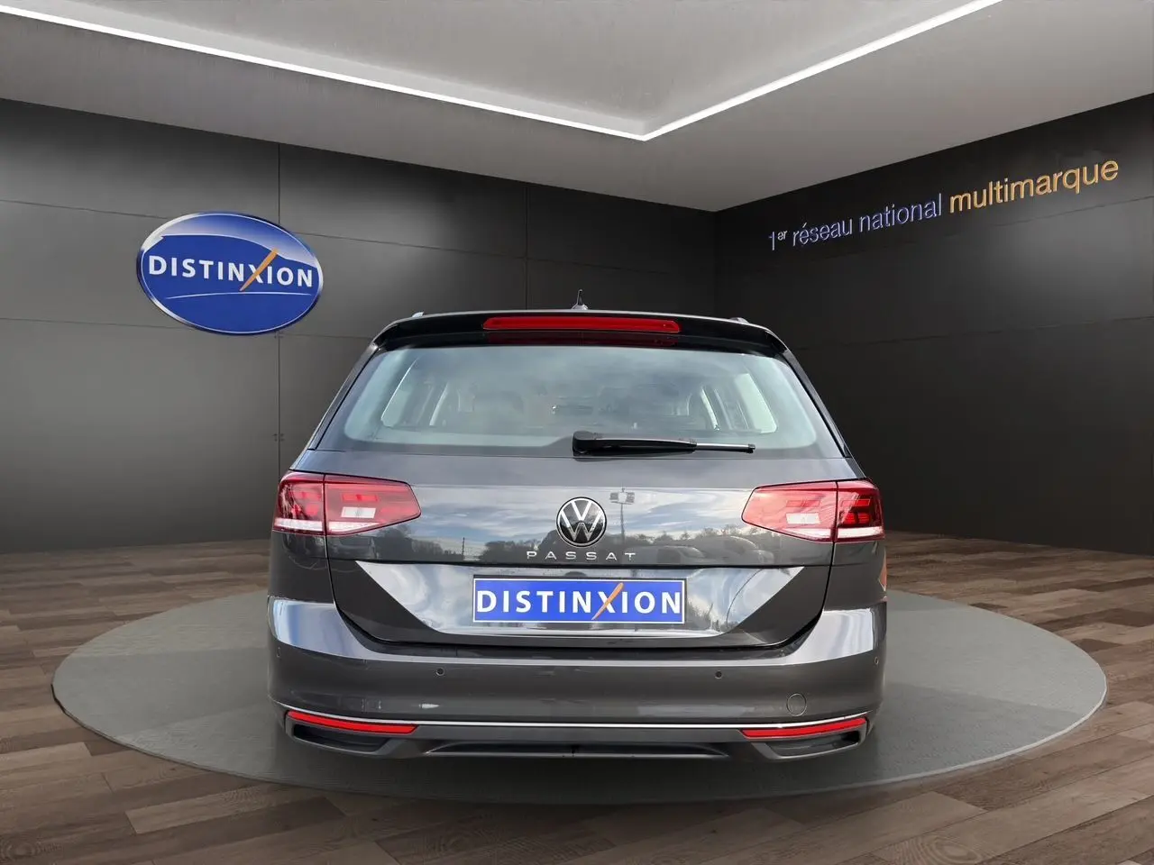 Vue arrière d'une Volkswagen Passat SW gris manganèse avec caméra de recul, sur fond intérieur showroom.