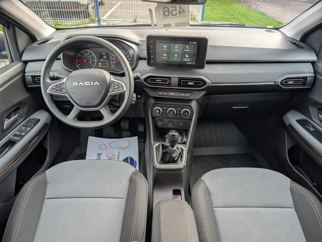 Vue intérieure avant du Dacia Jogger 2025, tableau de bord noir avec écran tactile et volant multifonction gris.