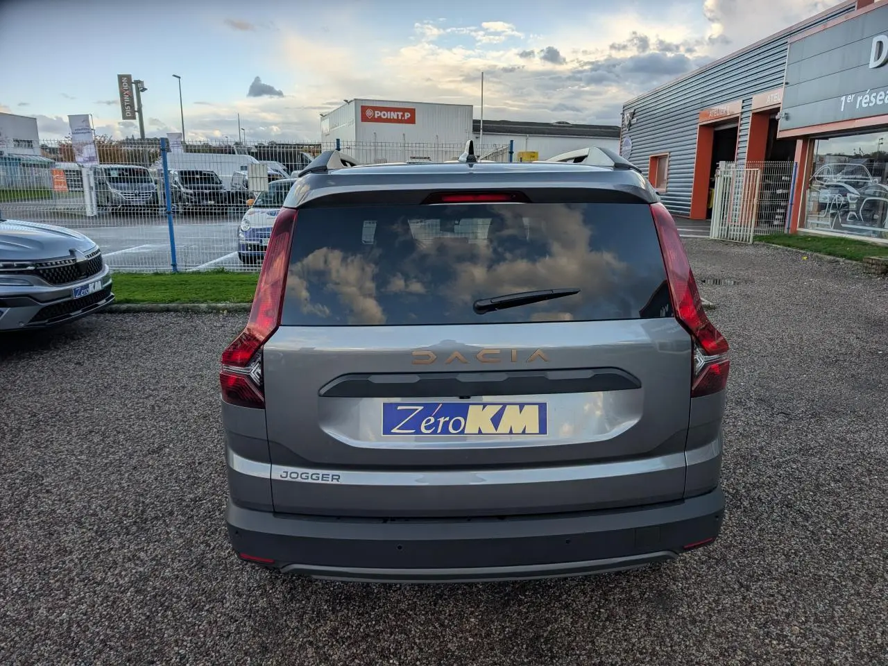 Vue arrière d’un Dacia Jogger gris métallisé avec logo brun cuivré et plaque Zéro KM visible.