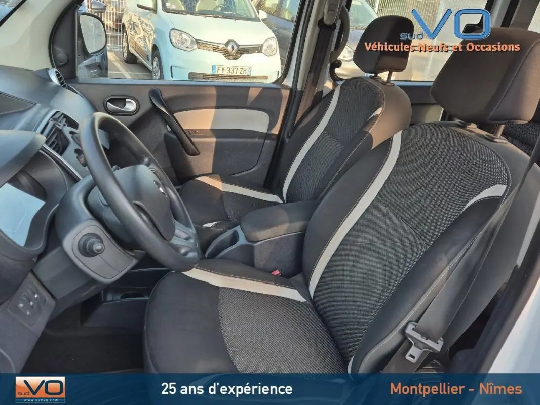 Intérieur avant du Renault Kangoo blanc 2016, sièges bi-ton noirs et gris, volant et tableau de bord visibles.