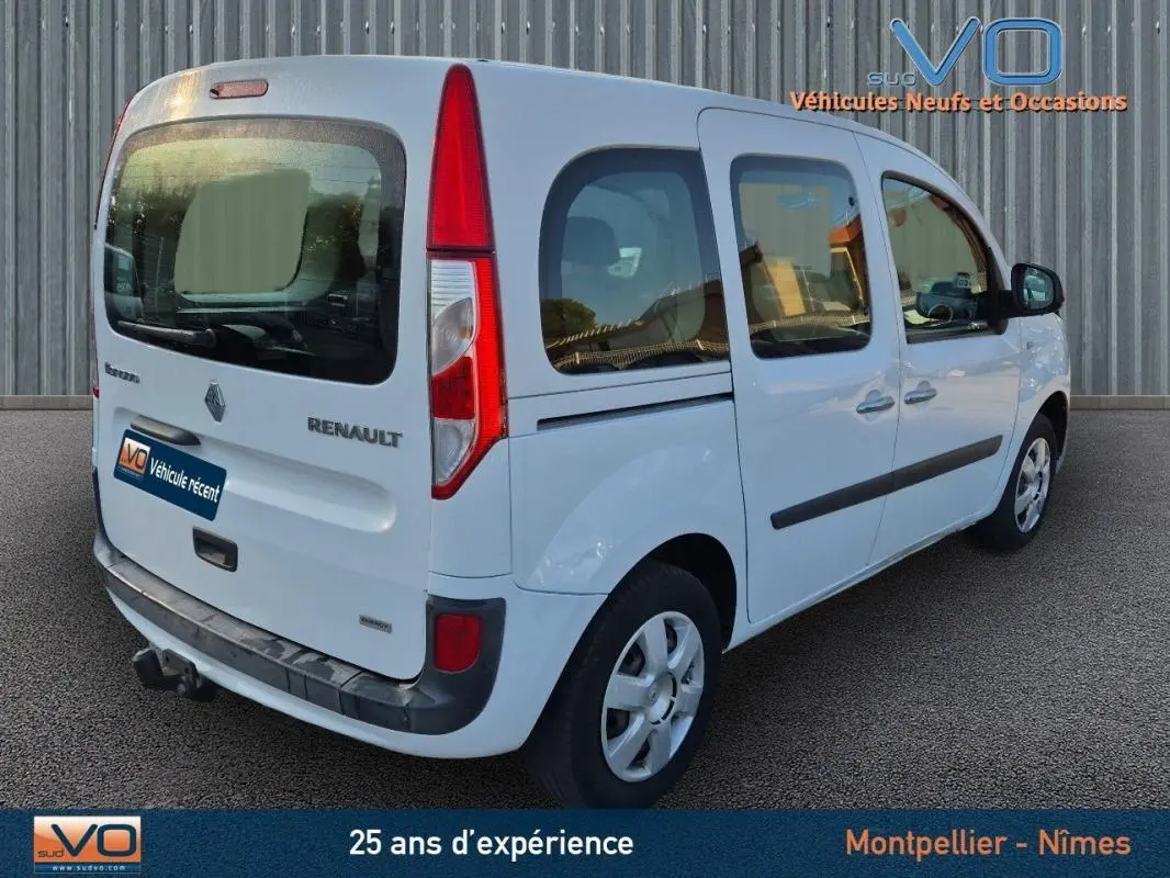 Renault Kangoo blanc vu en 3/4 arrière droit, avec vitres surteintées et porte latérale coulissante visible.