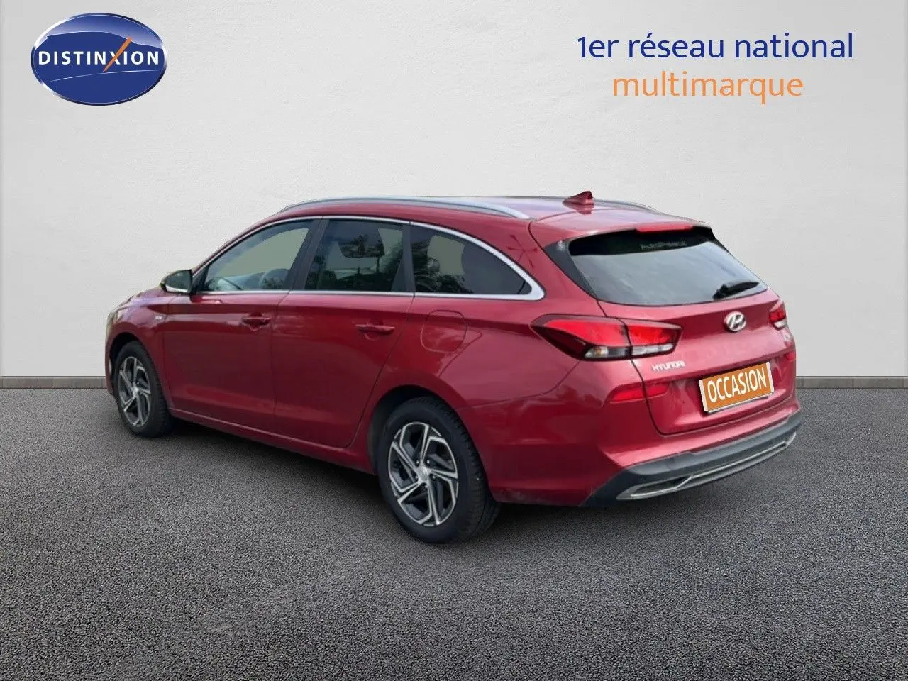 Vue 3/4 arrière droite d'une Hyundai i30 SW 2023 en rouge Sunset Metal avec jantes bi-ton et feux LED distinctifs.