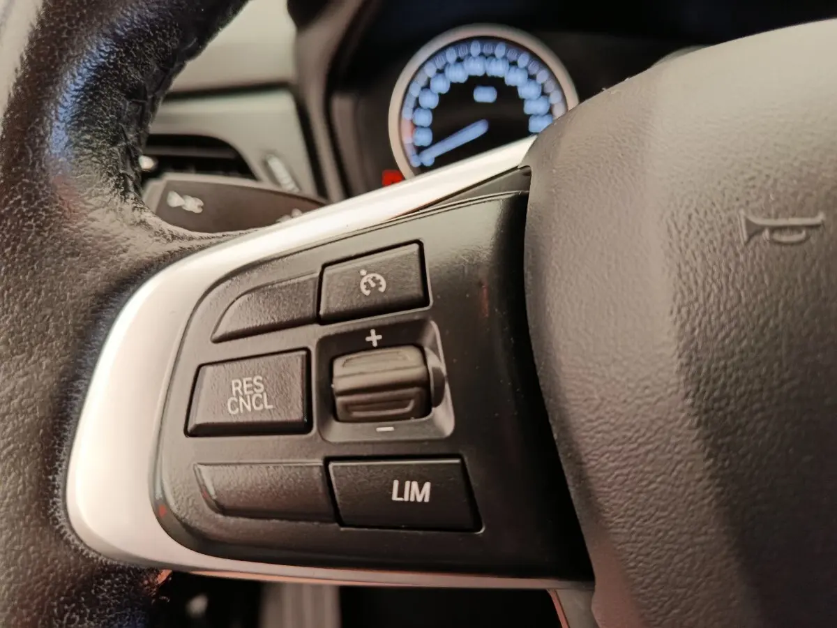 Gros plan sur le volant cuir et alu de la BMW Série 2 Gran Tourer gris clair, avec commandes multifonctions visibles.