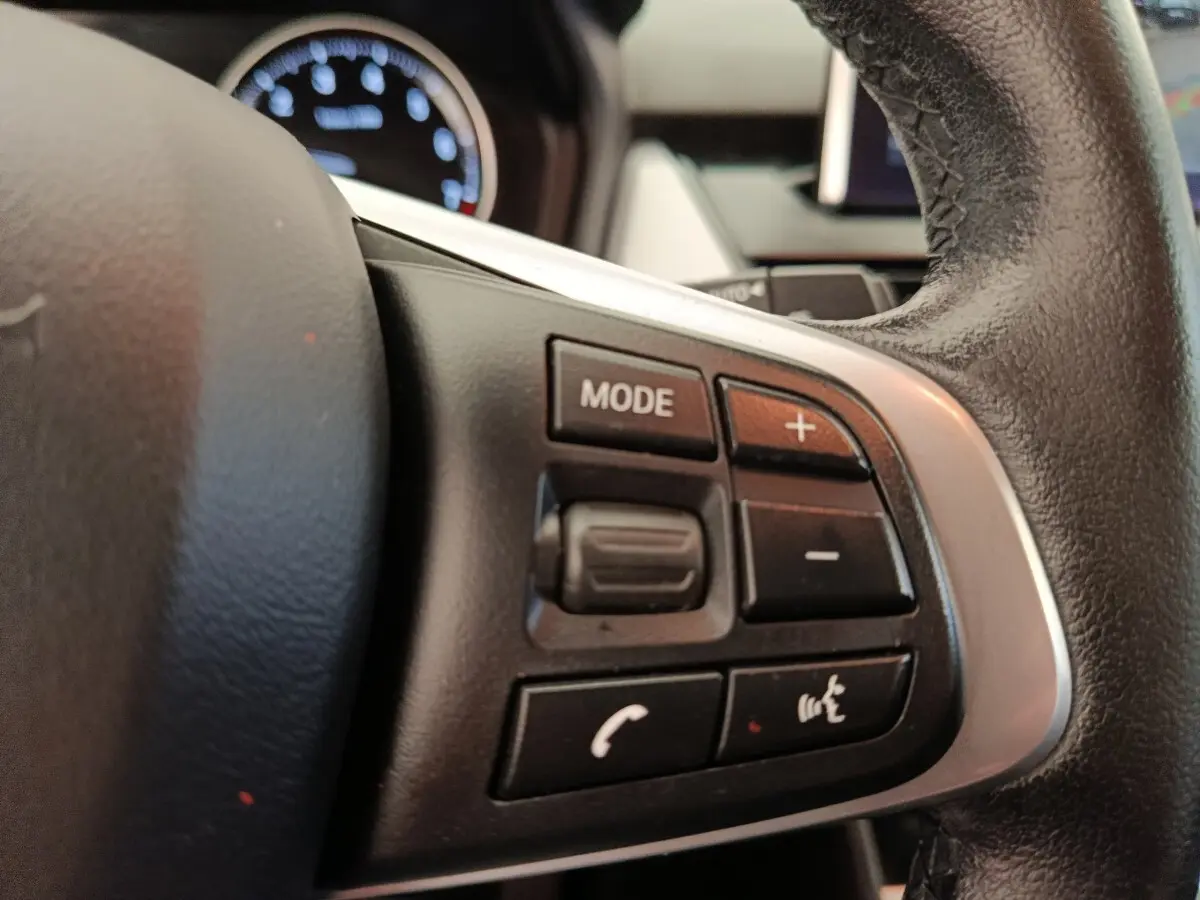 Gros plan sur le volant cuir et alu avec commandes multifonctions du BMW Série 2 Gran Tourer gris clair 218i Lounge.