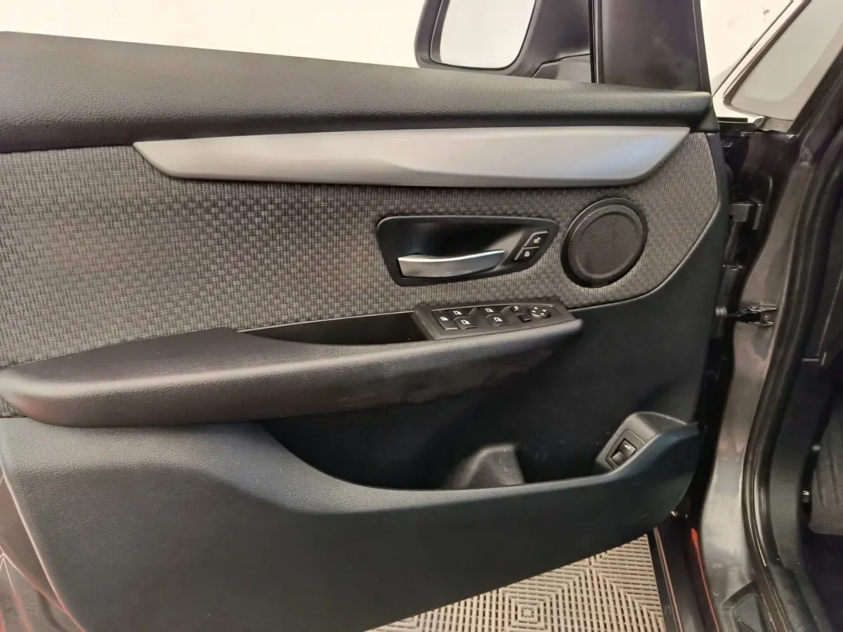 Vue intérieure côté gauche de la porte avant grise d'une BMW Série 2 Gran Tourer avec garniture tissu et commandes électriques.