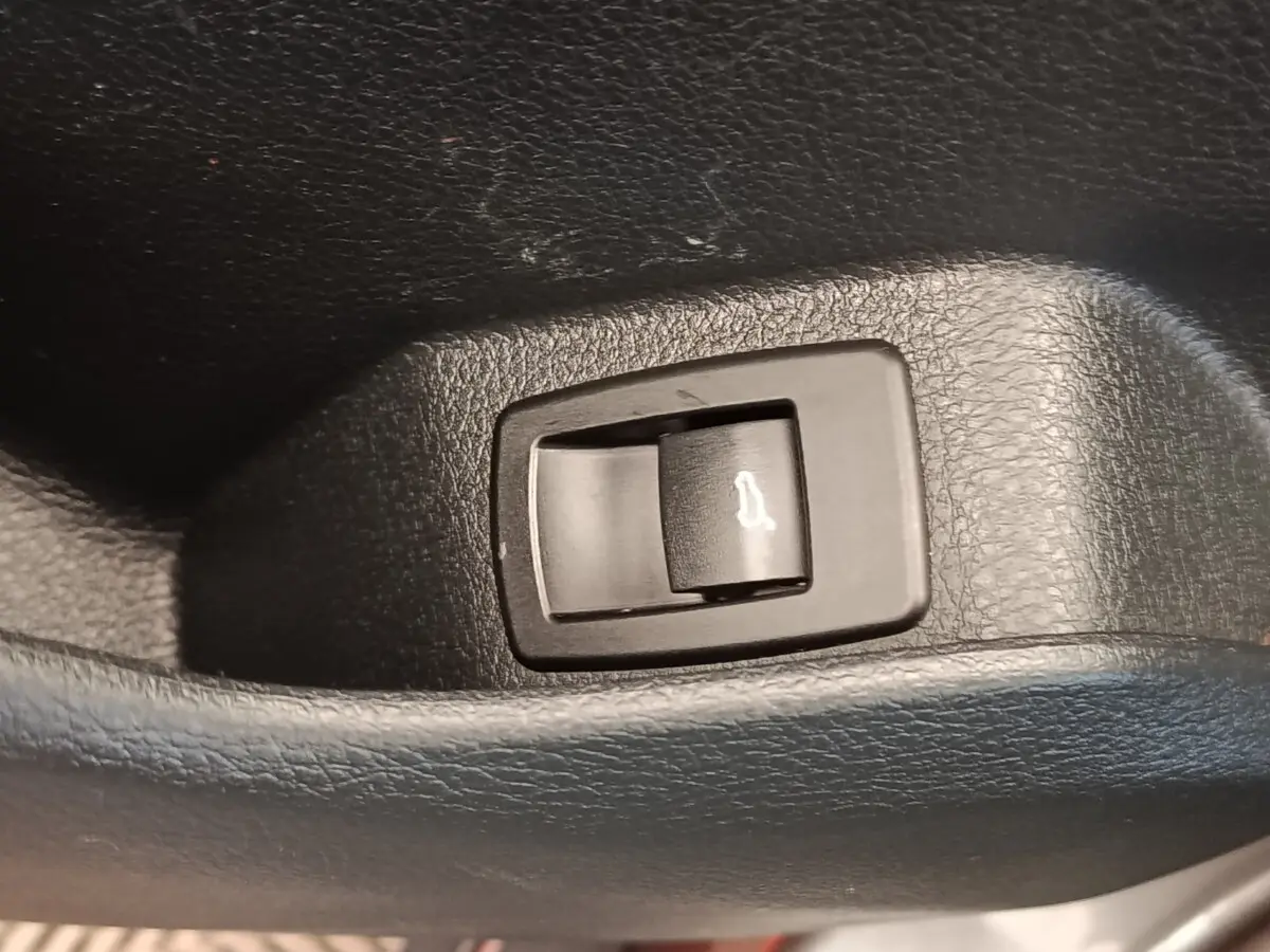 Gros plan sur le bouton d'ouverture électrique du coffre intérieur d'une BMW Série 2 Gran Tourer gris clair.