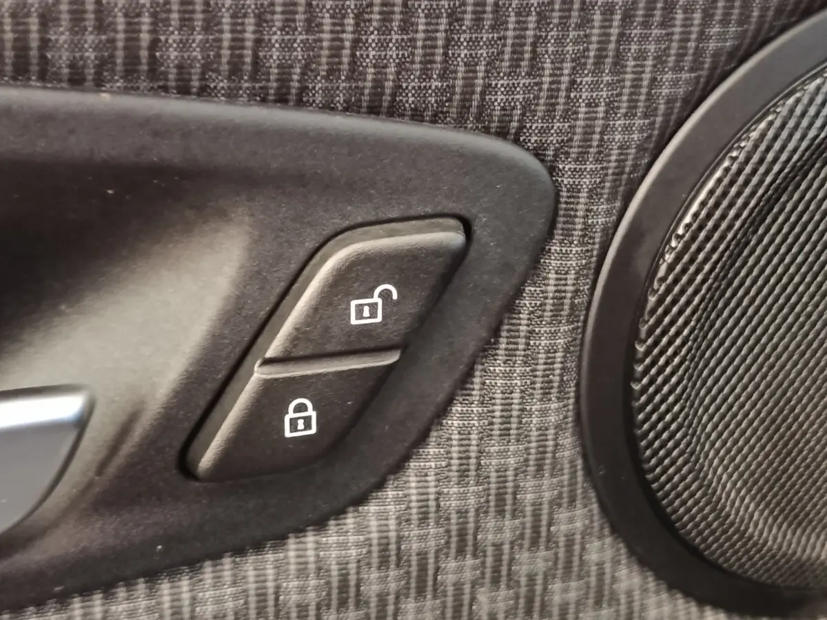 Gros plan sur les boutons de verrouillage centralisé sur la garniture de porte intérieure grise d'une BMW Série 2 Gran Tourer.