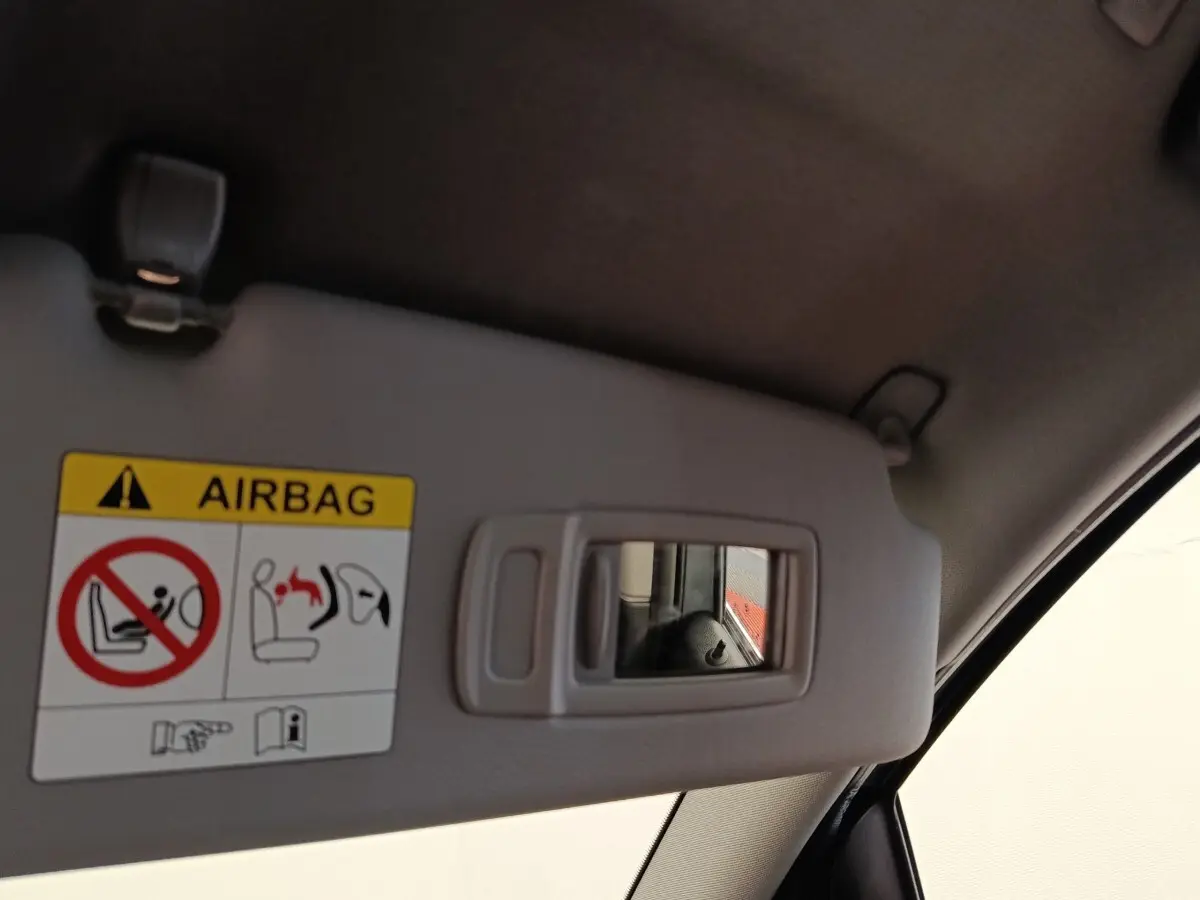 Détail du pare-soleil côté conducteur avec miroir intégré et avertissement airbag dans une BMW Série 2 Gran Tourer gris clair.