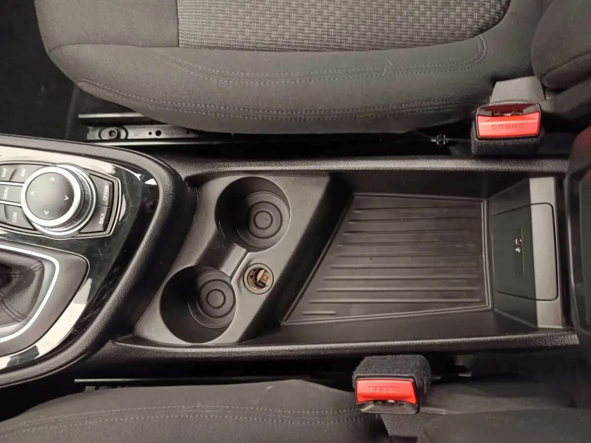 Vue plongeante sur la console centrale noire avec porte-gobelets et commande iDrive d'une BMW Série 2 Gran Tourer gris clair.