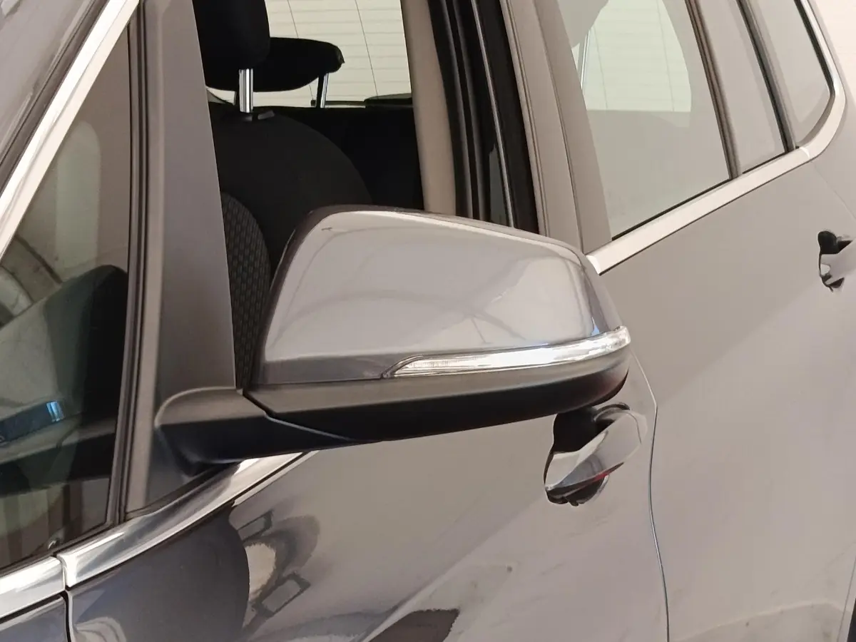 Gros plan sur le rétroviseur et la poignée côté conducteur d'une BMW Série 2 Gran Tourer gris clair.