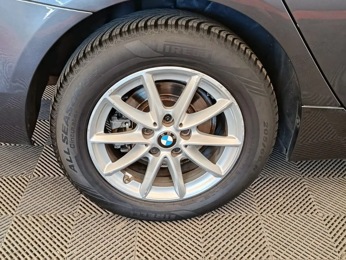 Gros plan sur la roue avant gauche grise claire d’une BMW Série 2 Gran Tourer F46 avec jante alu à 7 branches.