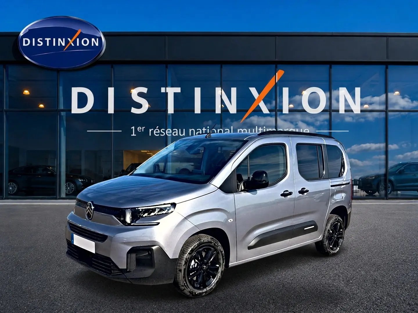 Citroën Berlingo Steel Grey en 3/4 avant droit, avec jantes noires et barres de toit visibles devant showroom Distinxion.