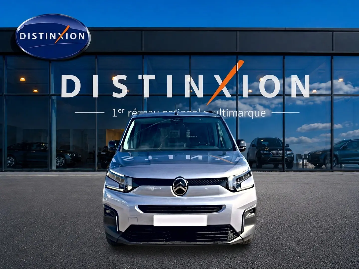 Vue avant d'un Citroën Berlingo 2026 gris acier, avec calandre moderne et phares LED devant un showroom Distinxion.