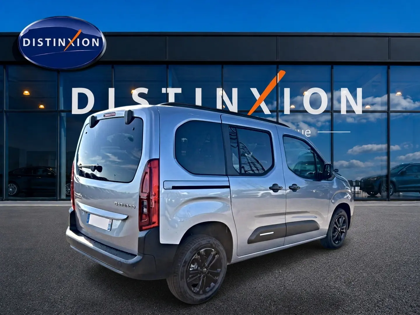 Vue 3/4 arrière droite d’un Citroën Berlingo Steel Grey avec barres de toit et jantes alu noires.