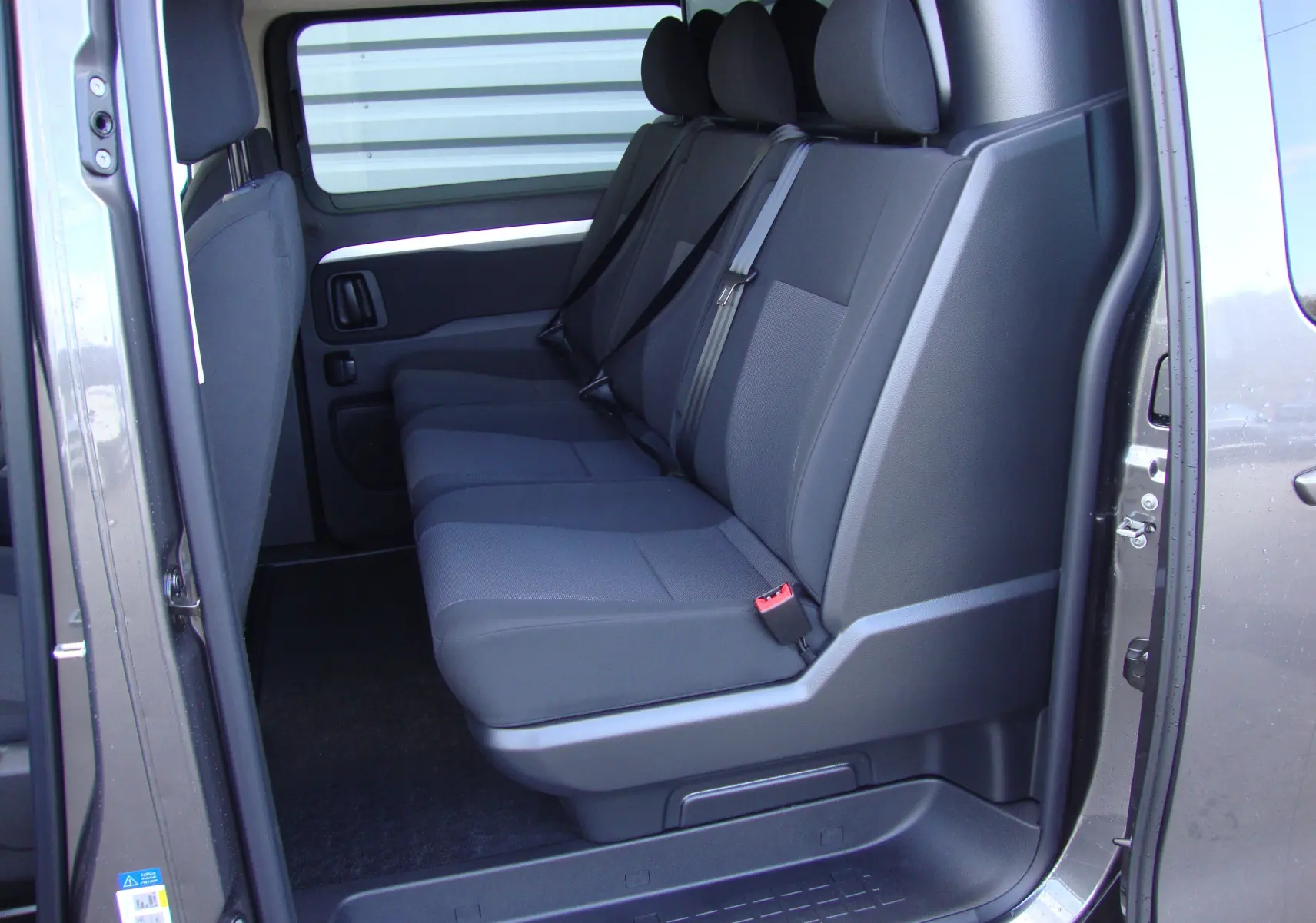 Vue latérale intérieure montrant les sièges arrière noirs du Citroën Jumpy Cabine Approfondie gris platinum 2024.