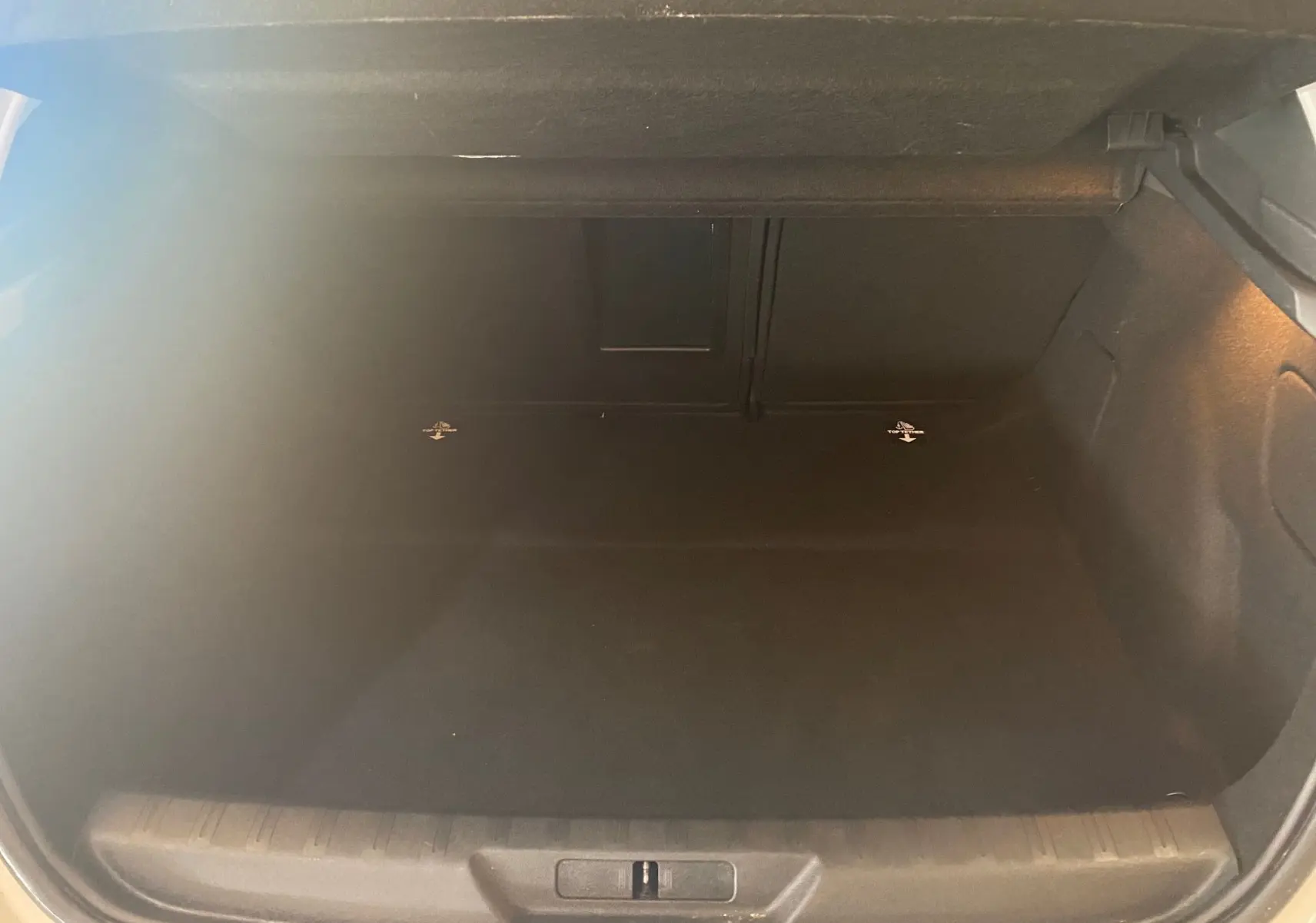 Coffre ouvert en vue arrière d'une Peugeot 308 blanche, montrant un espace de chargement vide et propre.