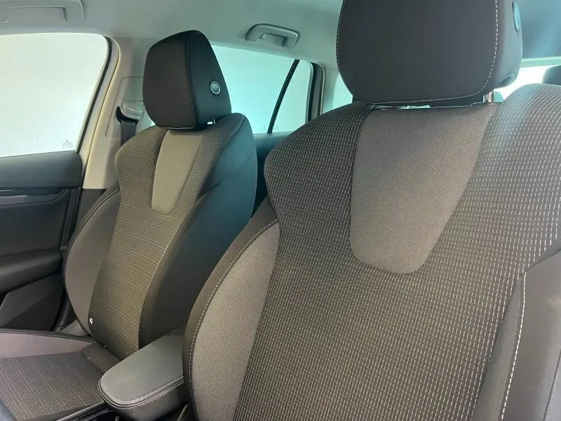 Gros plan sur les sièges avant en tissu noir du Skoda Octavia Combi 2022, avec accoudoir central visible.