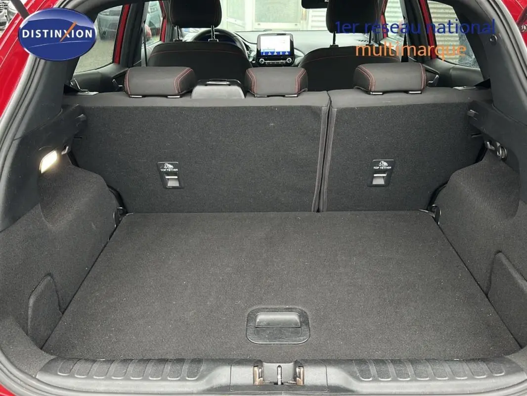 Coffre ouvert d'un Ford Puma rouge 2020, vue arrière montrant l'espace de chargement et les sièges arrière rabattus.