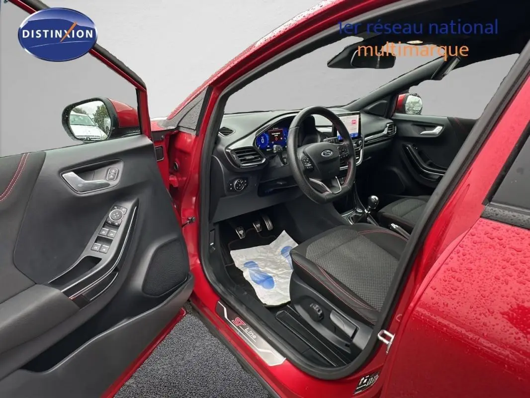 Intérieur côté conducteur d'un Ford Puma rouge 2020, avec sellerie noire et détails ST-Line visibles sur le seuil de porte.