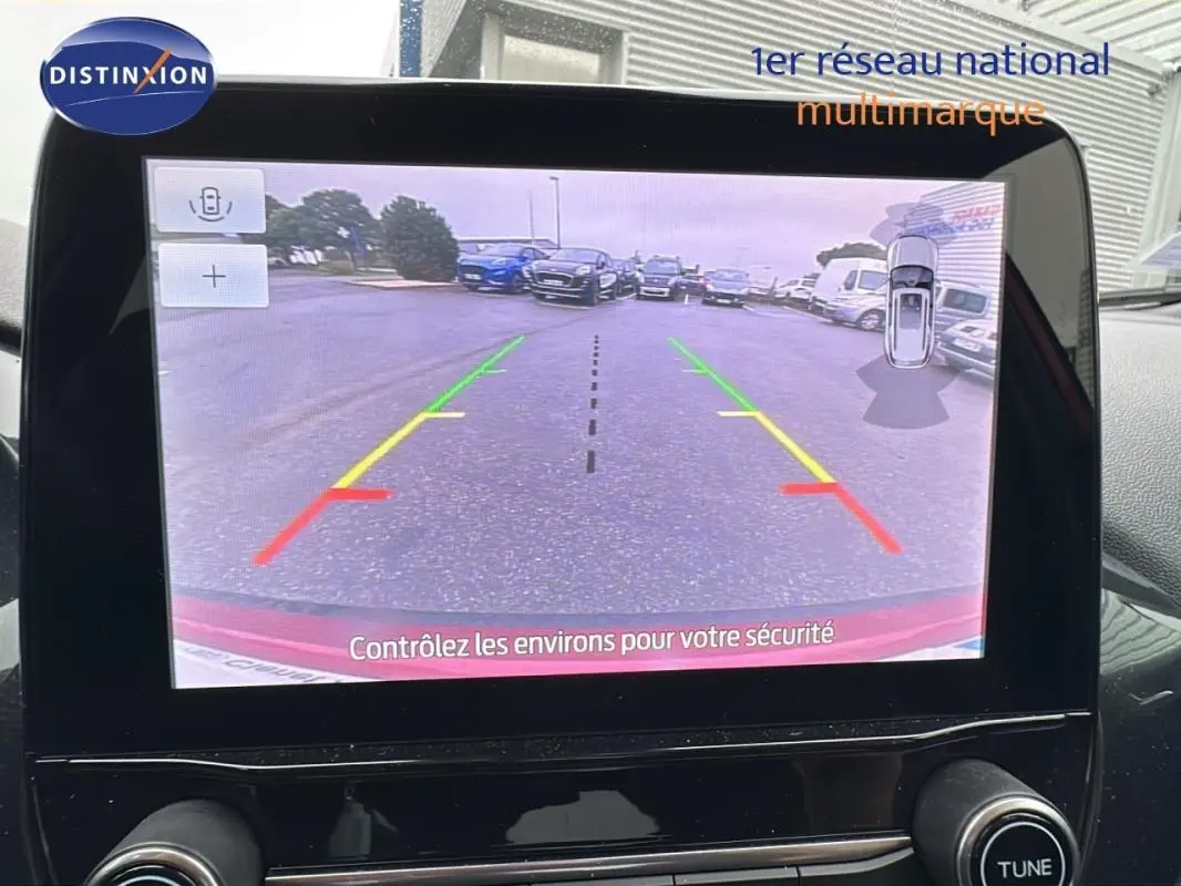 Écran tactile du Ford Puma rouge montrant la caméra de recul avec lignes de guidage colorées en extérieur.