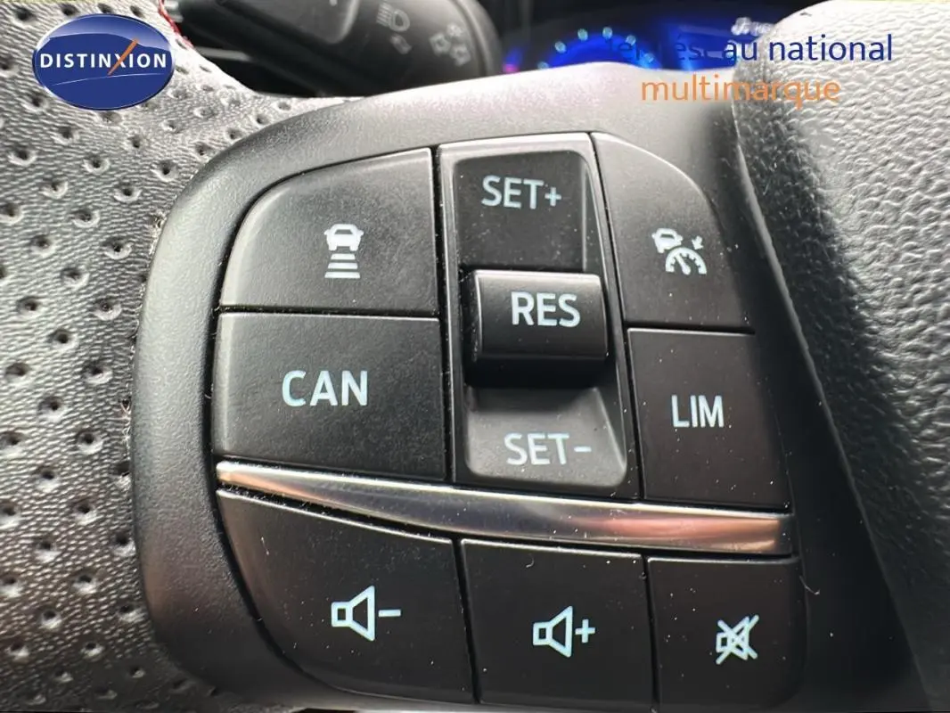 Gros plan sur les commandes au volant de la Ford Puma rouge 2020, mettant en valeur les boutons du régulateur de vitesse et du volume sonore.