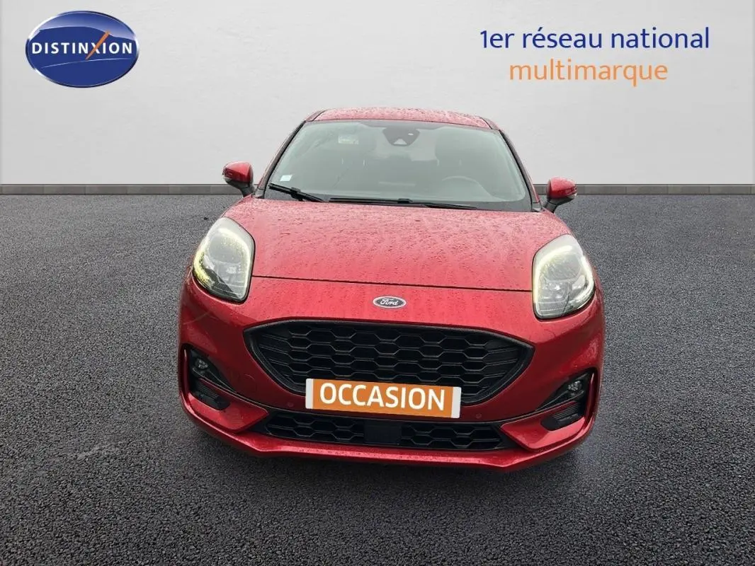 Vue frontale d'une Ford Puma rouge 2020 avec calandre noire et feux allumés sur sol asphalté.