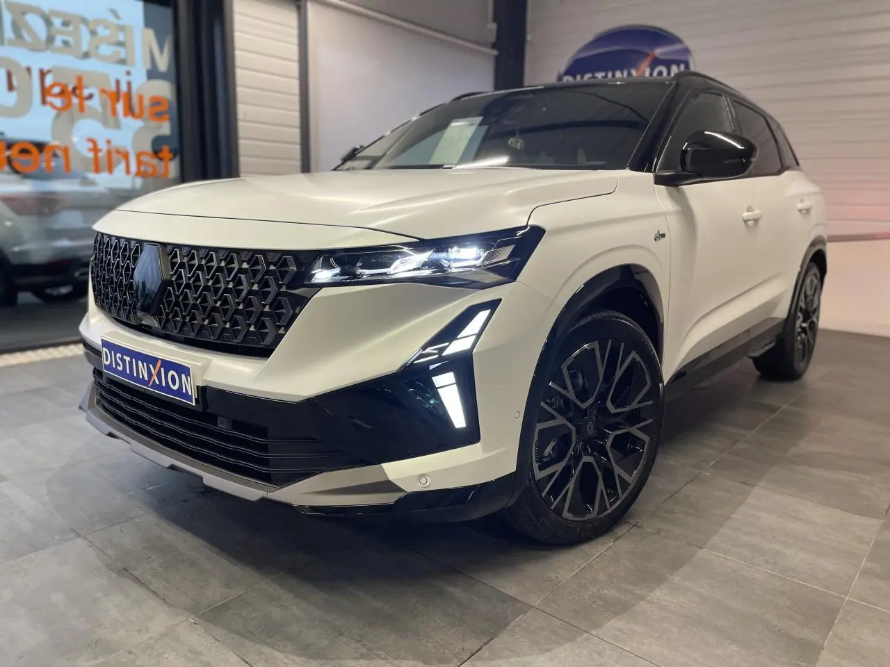 Renault Austral blanc nacré satin avec toit noir, vue 3/4 avant droit, calandre noire et jantes diamantées.